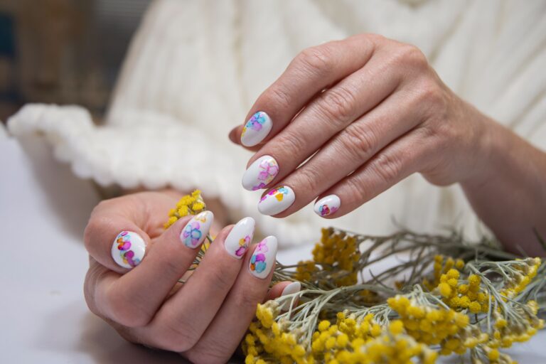 hands with beautiful multi colored manicure hold bouquet yellow flowers min
